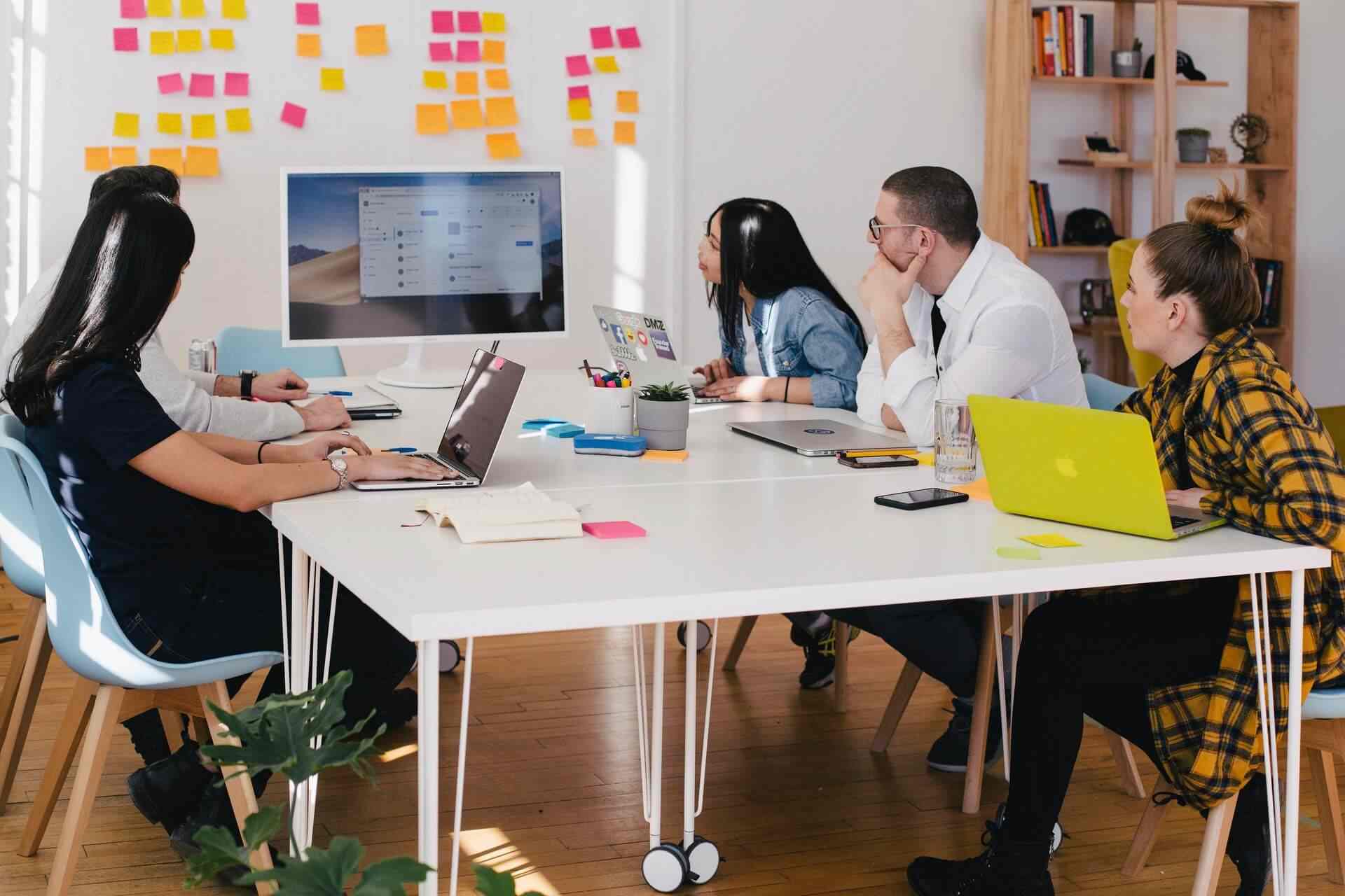 Five people sitting at a table, in a meeting, discussion the Customer Journey